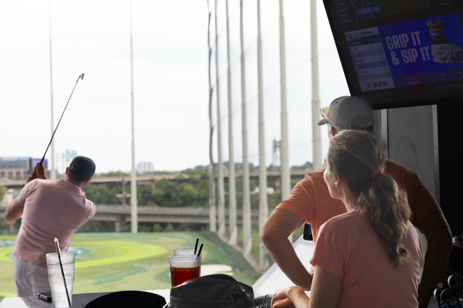 A Spark golfer swinging in a Topgolf hitting bay
