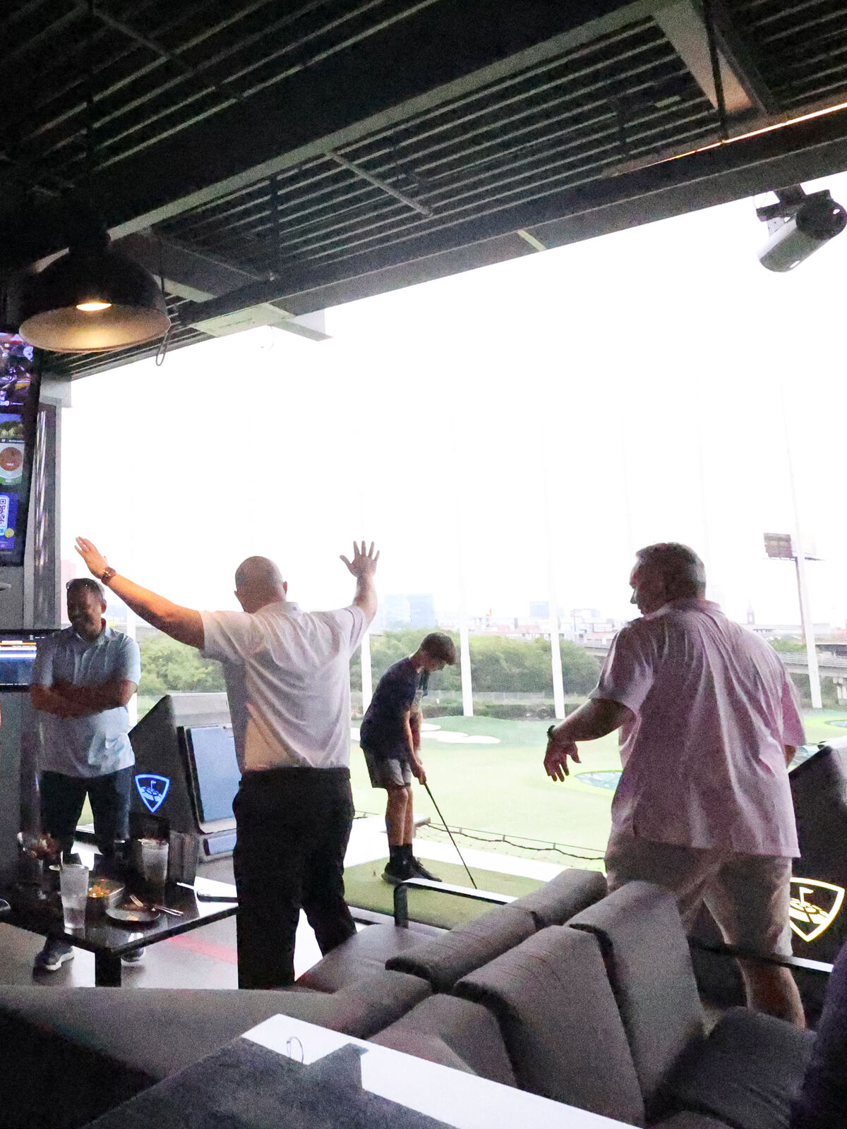 Spark golfers cheering a shot in a Topgolf hitting bay